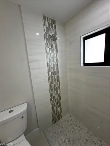 Full bath with a tile shower and toilet