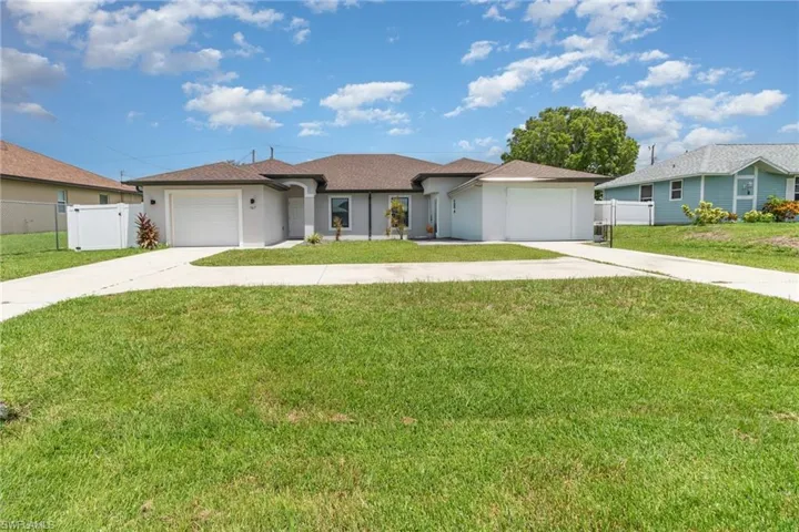 View of front of home with a garage, a gate, stucco siding, and driveway
