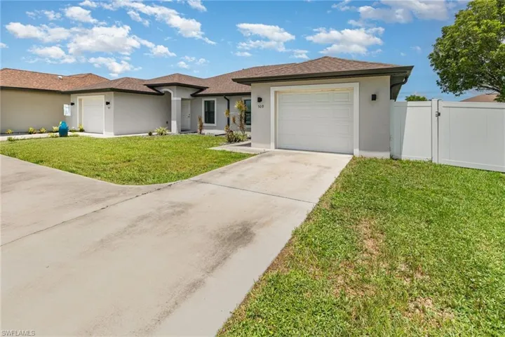 View of front of property featuring an attached garage, a gate, stucco siding, driveway, and a shingled roof