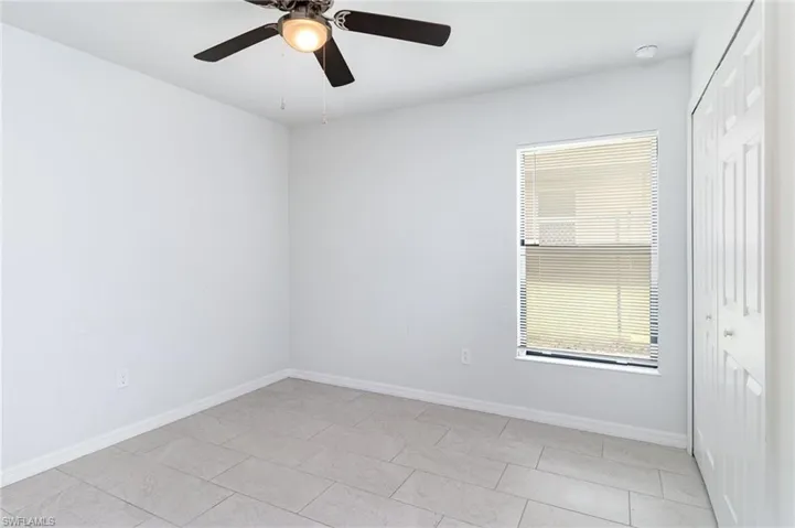 Unfurnished bedroom with a closet, light tile patterned flooring, and ceiling fan
