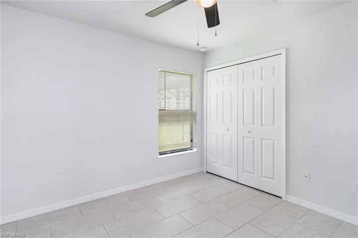 Unfurnished bedroom with a closet, a ceiling fan, and light tile patterned flooring