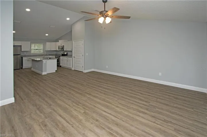 Spacious open-concept living area featuring vaulted ceilings, wood-finish flooring, and recessed lighting