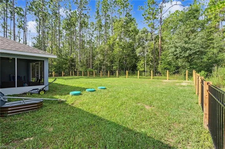Expansive green space with perimeter fencing and a screened-in patio