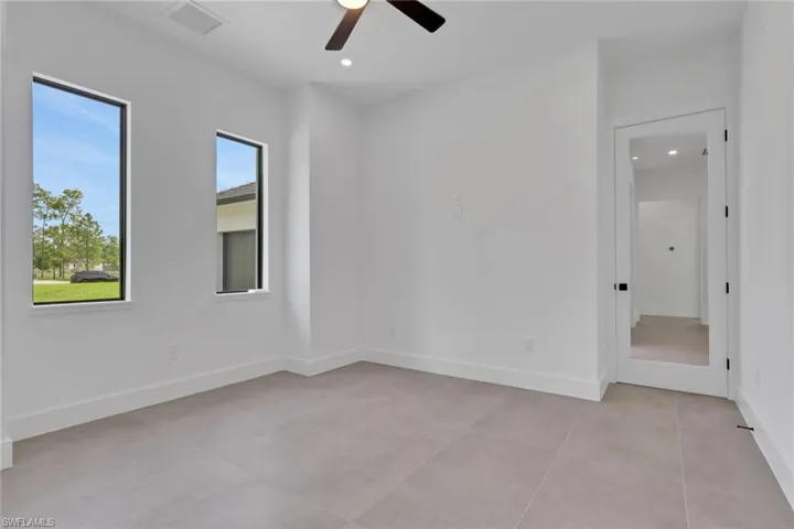 Contemporary room featuring two rectangular windows, light gray tile flooring, white baseboards, and a modern ceiling fan with lighting