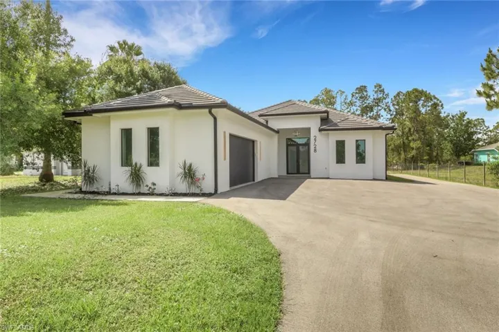 Modern architectural exterior featuring white stucco, dark trim, and a concrete tile roof