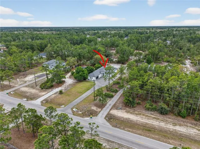 Aerial property capture featuring a single-story residence with a dark roof and white exterior