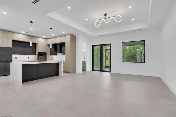 Open concept living space featuring a contemporary kitchen with a waterfall island, two-tone cabinetry, and integrated appliances