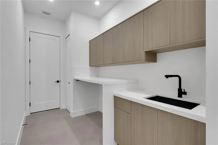 Laundry area featuring light wood-finish cabinetry and white countertops