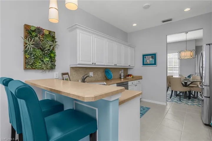 Kitchen with pendant lighting, a peninsula, a breakfast bar, light countertops, and appliances with stainless steel finishes