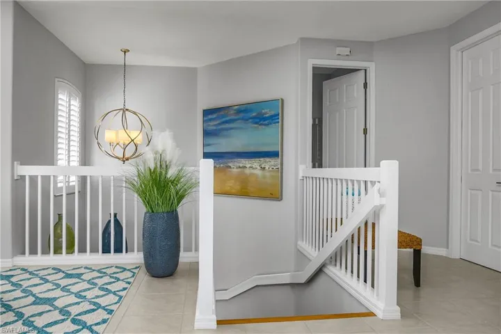 Corridor featuring an upstairs landing, light tile patterned floors, and a chandelier