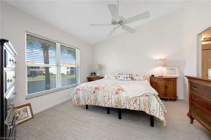 Carpeted bedroom featuring ceiling fan and lofted ceiling