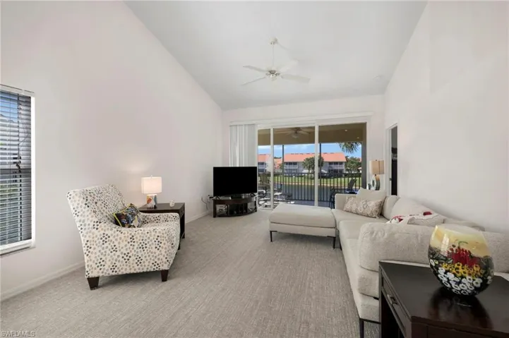 Living room featuring high vaulted ceiling, ceiling fan, and carpet flooring