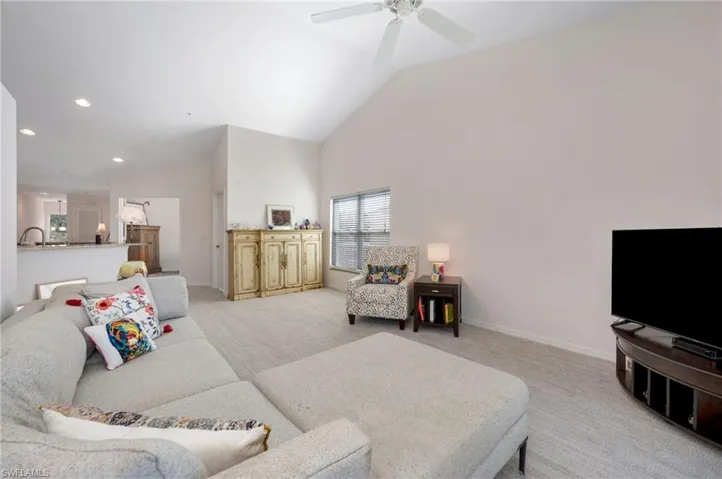 Carpeted living room featuring high vaulted ceiling and ceiling fan