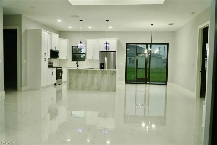 Kitchen featuring a center island, white cabinets, appliances with stainless steel finishes, decorative light fixtures, and recessed lighting