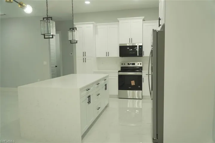 Kitchen with stainless steel appliances, white cabinetry, light marble finish flooring, pendant lighting, and recessed lighting