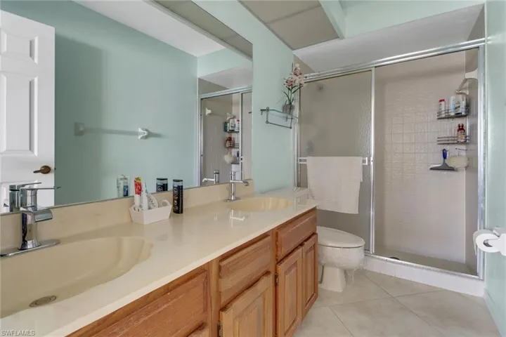 Bathroom featuring tile patterned flooring, vanity, toilet, and walk in shower