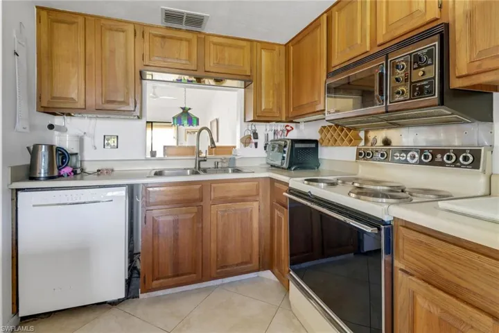 Kitchen with sink, white appliances, and light tile patterned floors