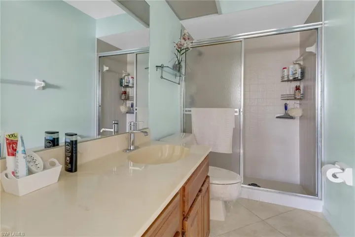 Bathroom with vanity, a shower with shower door, tile patterned floors, and toilet