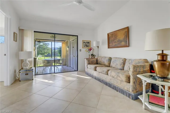 Living room featuring vaulted ceiling, ceiling fan, and light tile patterned flooring