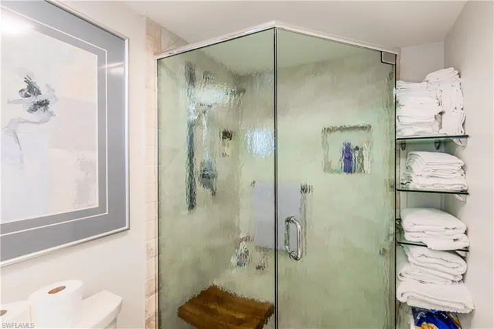 Bathroom featuring a shower with shower door and toilet