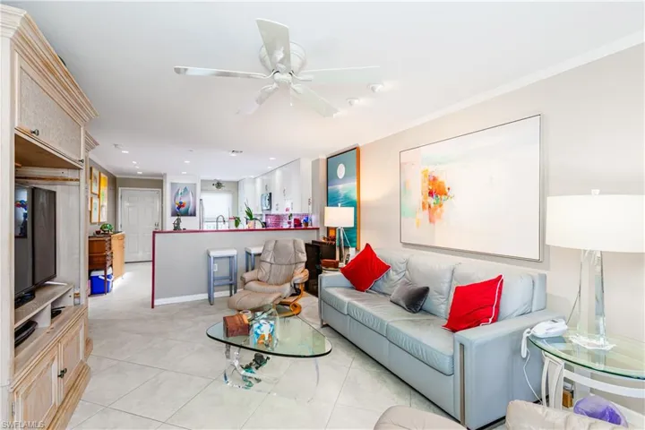 Living room featuring ceiling fan, light tile patterned floors, and ornamental molding