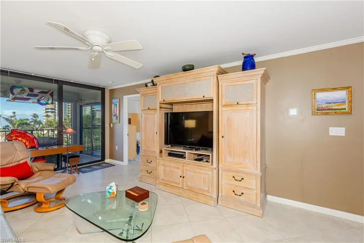 Tiled living room featuring ceiling fan and crown molding