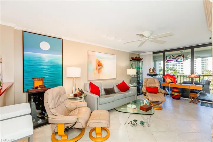 Living room featuring light tile patterned floors, expansive windows, ceiling fan, and ornamental molding