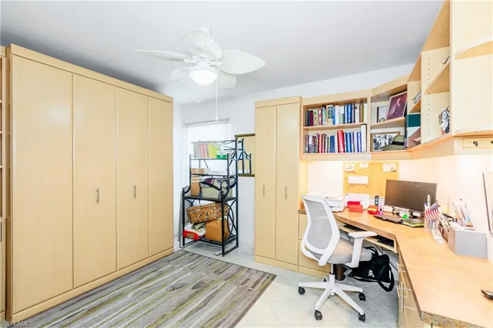 Tiled office space with ceiling fan and built in desk