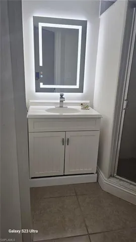 Bathroom featuring vanity, a shower stall, dark tile patterned floors, and a textured wall