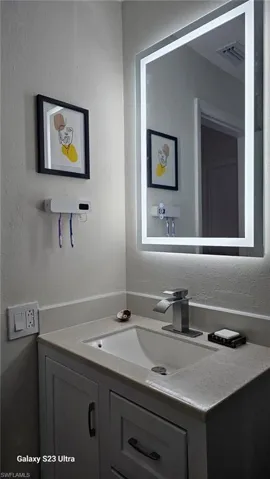 Bathroom featuring a textured wall and vanity