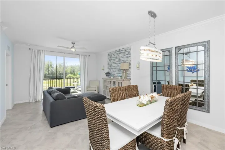 Dining area with light tile patterned floors, baseboards, crown molding, and ceiling fan