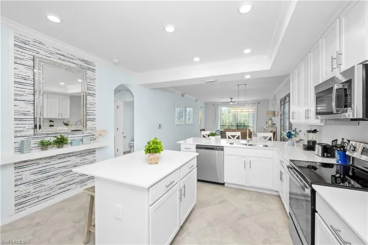 Kitchen featuring a sink, white cabinetry, stainless steel appliances, a peninsula, and crown molding