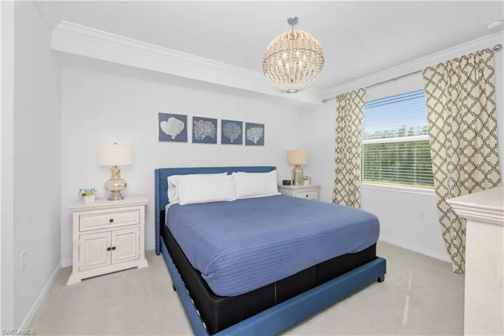 Bedroom with baseboards, light colored carpet, an inviting chandelier, and ornamental molding