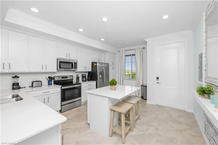 Kitchen featuring a kitchen island, a breakfast bar, ornamental molding, appliances with stainless steel finishes, and white cabinets