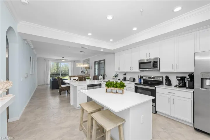 Kitchen with arched walkways, a peninsula, stainless steel appliances, and light countertops