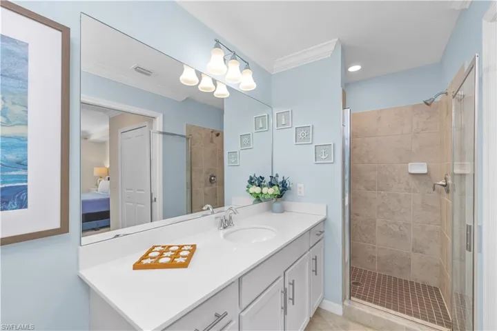 Ensuite bathroom with vanity, visible vents, a shower stall, ensuite bathroom, and crown molding
