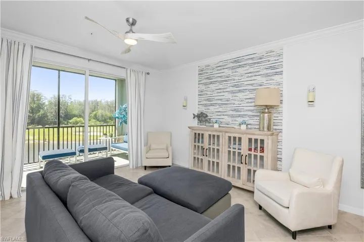 Living room featuring light tile patterned floors, a ceiling fan, baseboards, an accent wall, and crown molding