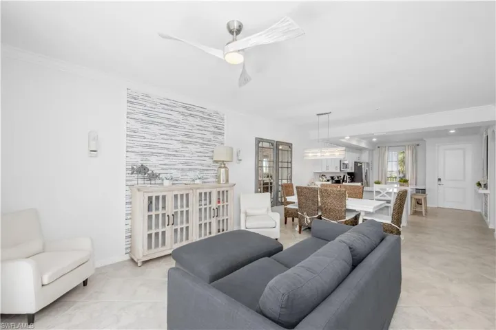 Living area with light tile patterned floors, baseboards, a ceiling fan, and crown molding