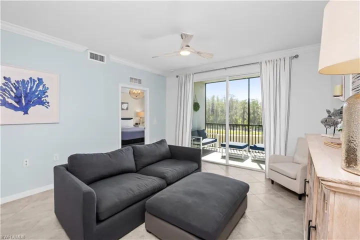 Living area with light tile patterned floors, visible vents, ceiling fan, and crown molding