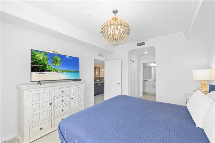 Bedroom featuring a chandelier, visible vents, ensuite bathroom, and crown molding