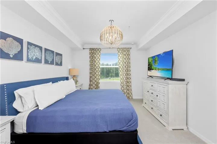 Bedroom featuring baseboards, light colored carpet, an inviting chandelier, and crown molding