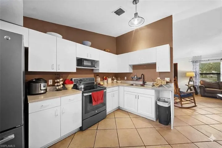 Kitchen featuring white cabinetry, light countertops, and a black appliance suite