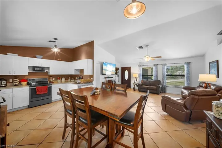 Open-concept living area featuring a kitchen with white cabinetry, a built-in microwave, and a black range