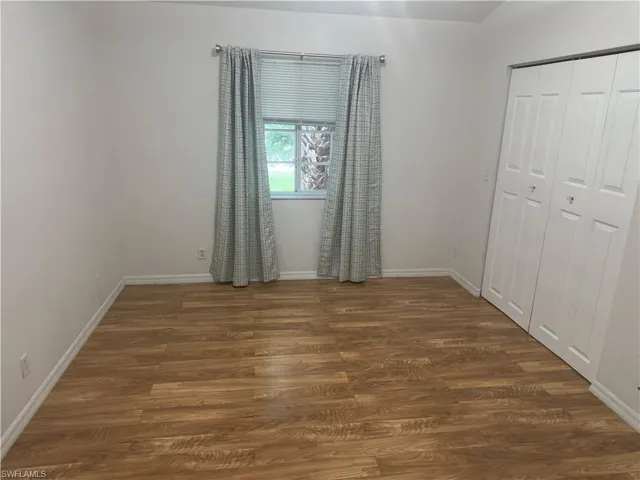 Bedroom featuring dark wood-style floors and a closet