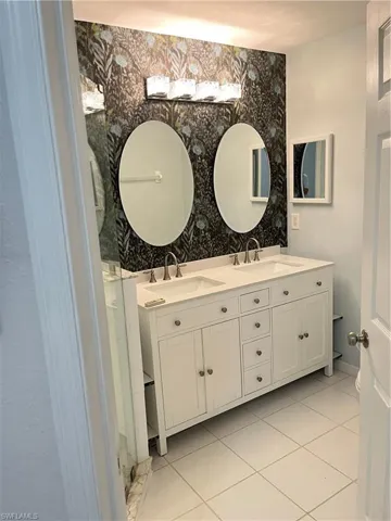 Full bathroom featuring wallpapered walls, double vanity, and tile patterned flooring