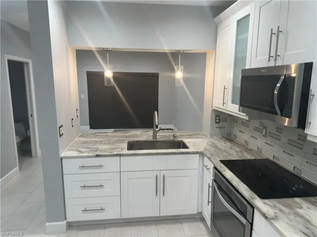 finishes, backsplash, light stone counters, white cabinets, and glass insert cabinets