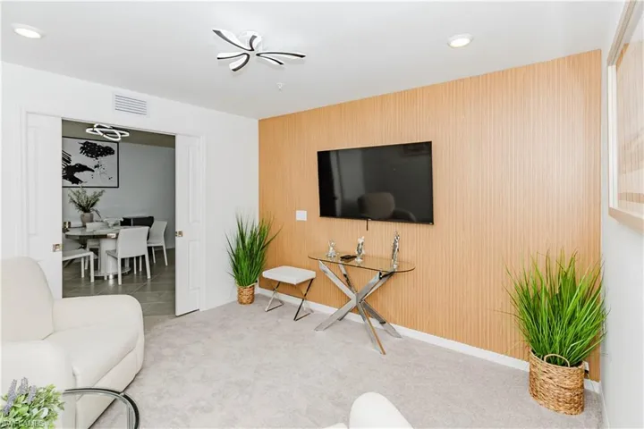 Carpeted living room with an accent wall and recessed lighting