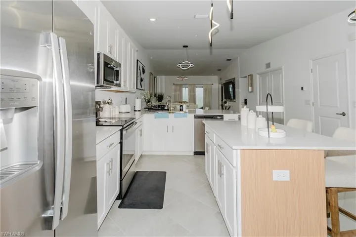 Kitchen with stainless steel appliances, a breakfast bar, a peninsula, light tile patterned floors, and light countertops