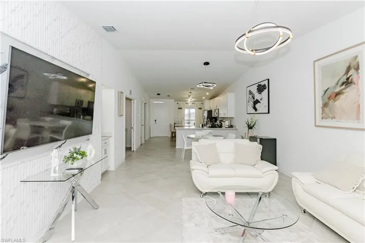 Living room with a chandelier, light tile patterned floors, and vaulted ceiling