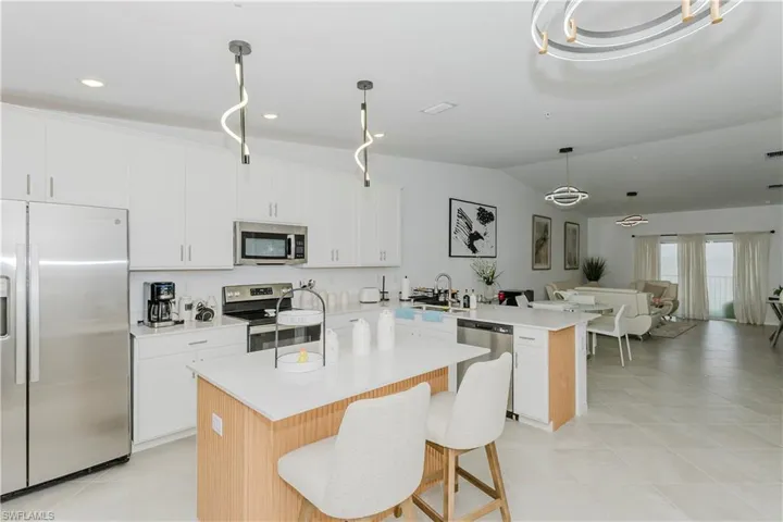 Kitchen with appliances with stainless steel finishes, a peninsula, light countertops, open floor plan, and light tile patterned flooring